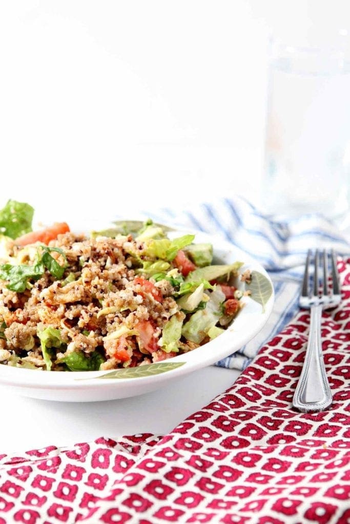 Summer Quinoa Salad in a white bowl with red and blue napkins surrounding it