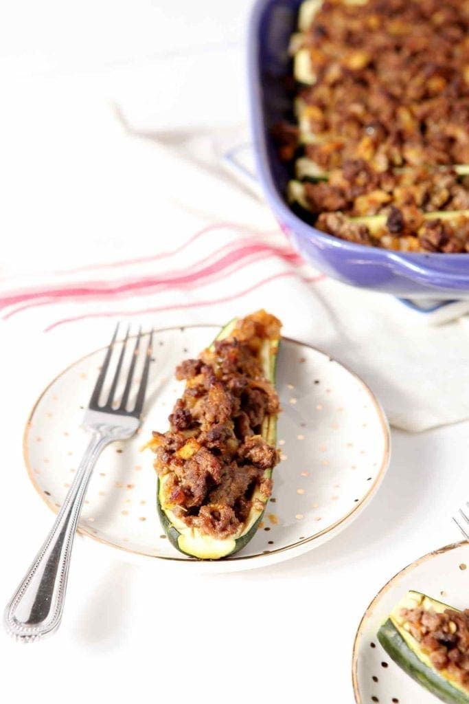 taco zucchini boat on a white plate with a fork