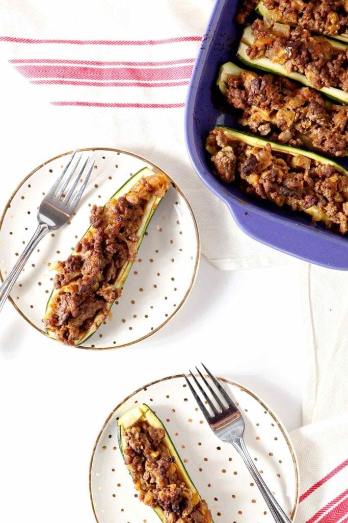 taco zucchin boat on a white plate with a fork