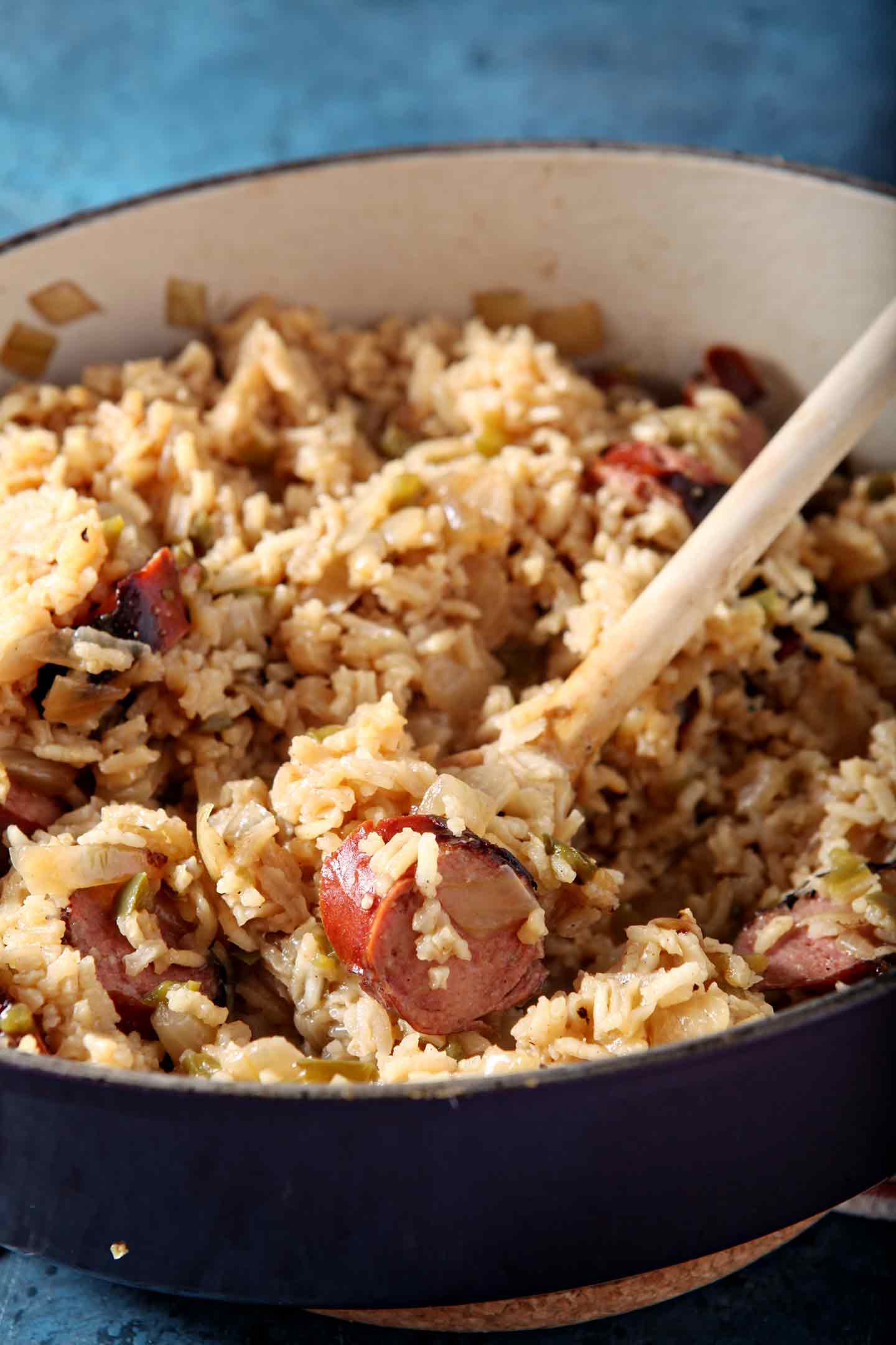 A Dutch oven of Jambalaya has a wooden spoon in it, close up