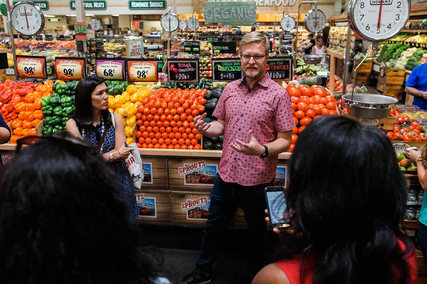 Man standing in front of produce stand talking 