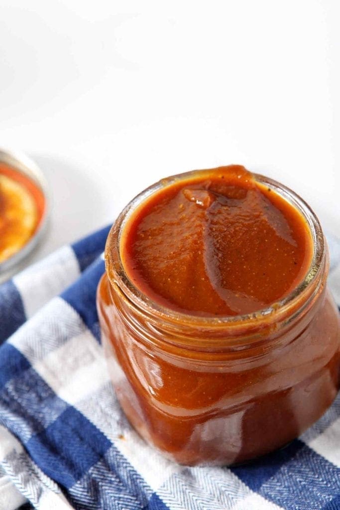 pumpkin barbecue sauce in a glass jar with a blue and white napkin