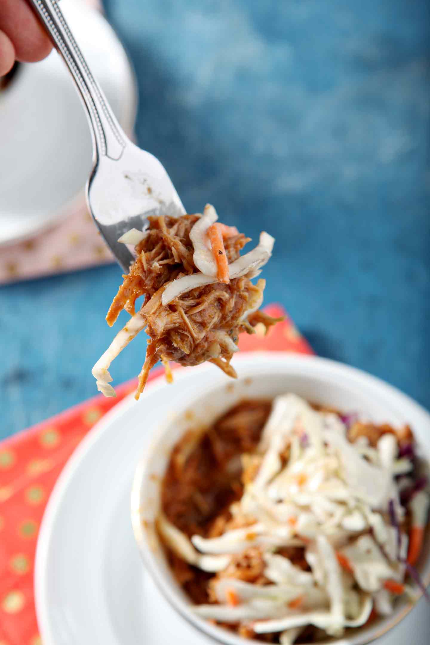 A fork holds a bite of the pumpkin pulled pork bowl with coleslaw.