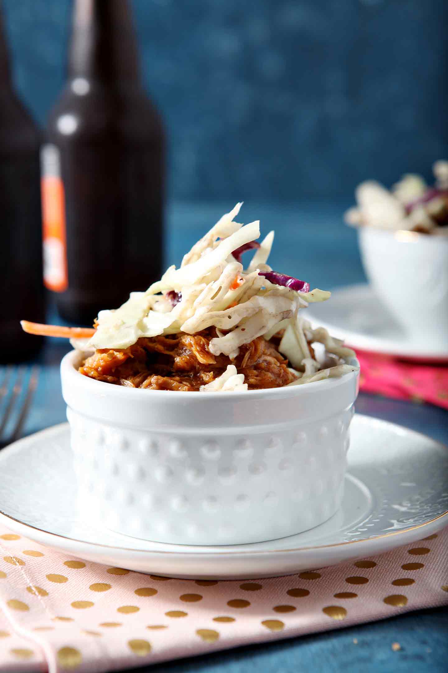 Close up of a pulled pork bowl, with beer bottles in the background