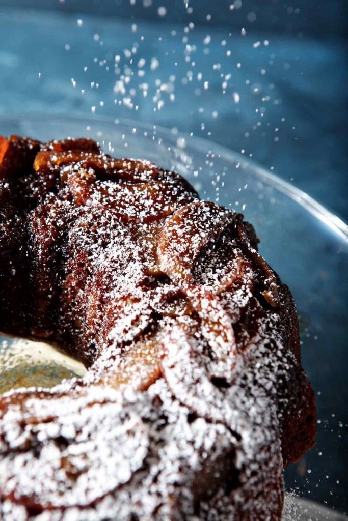 dusting powdered sugar on apple upside down cake 