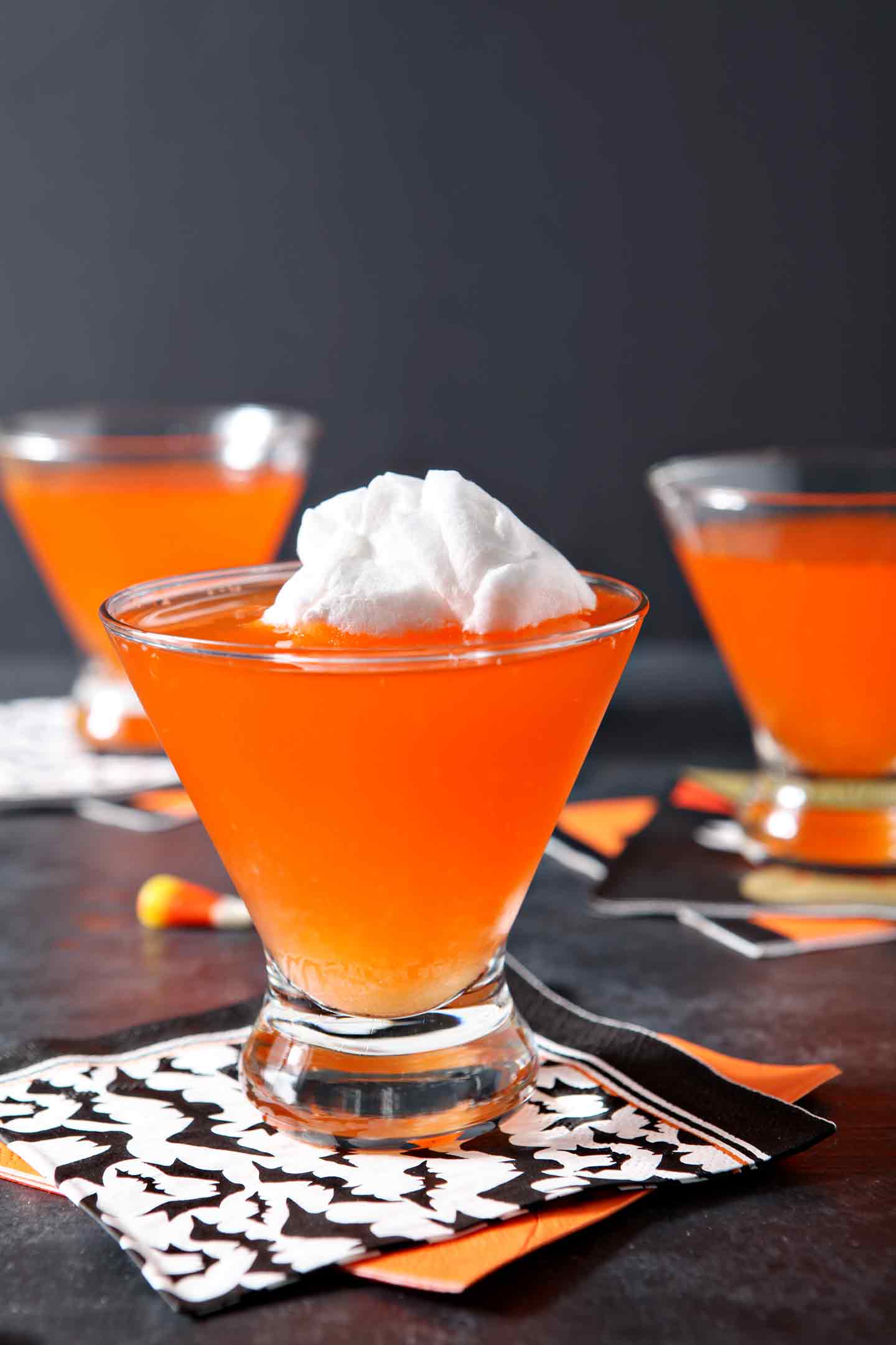 Three bright orange Candy Corn Martinis sit on a black background