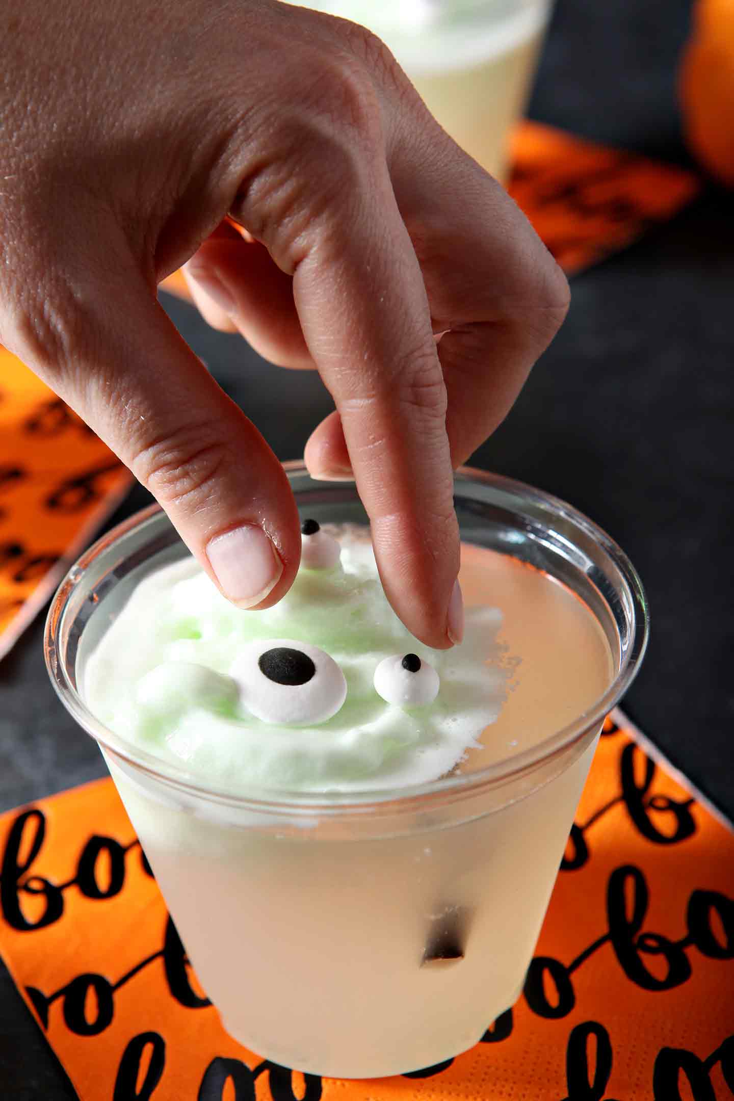 A woman drops candy eyeballs on top of the sherbert