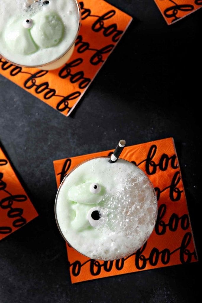 Two glasses of punch bubble on a black background with Halloween napkins