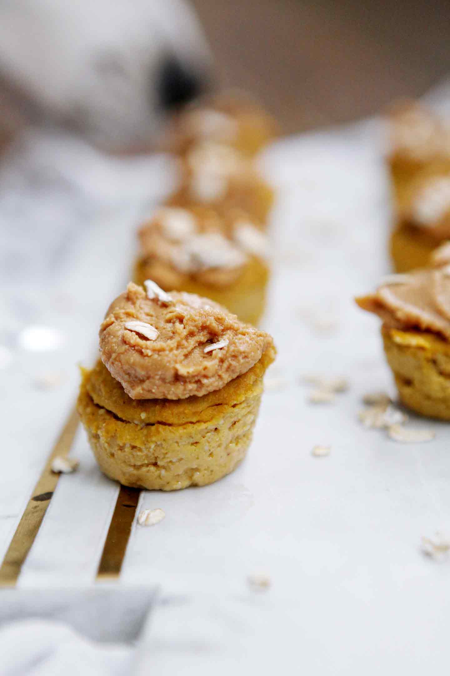 Close up of pumpkin pupcake recipe on a marble slab with a dog sniffing them in the background