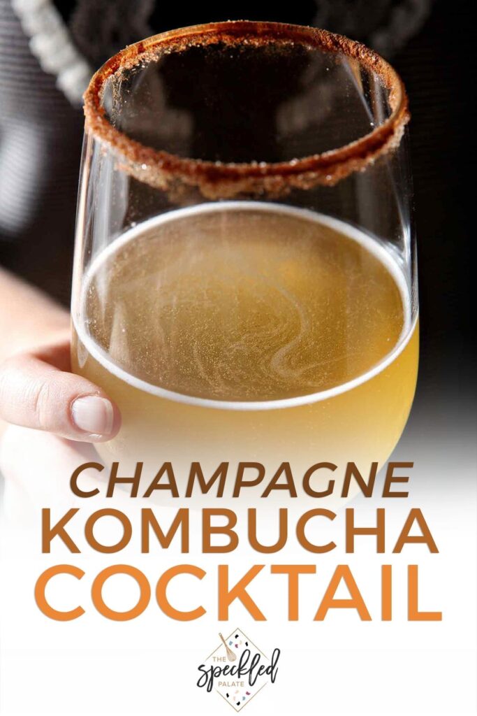 Close up of a woman holding a kombucha cocktail in a wine glass with the text 'champagne kombucha cocktail'