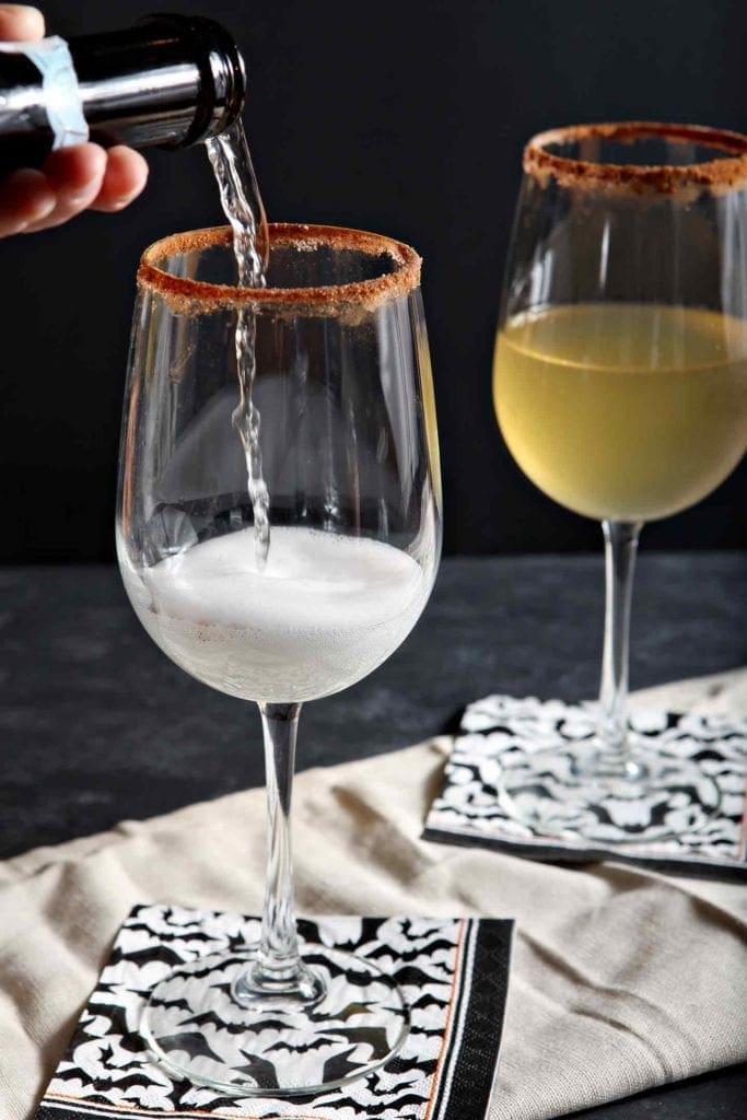 Prosecco pours into a wine glass on a dark background