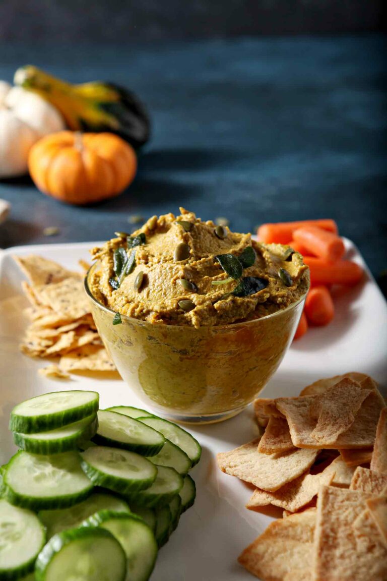 sage pumpkin hummus in a glass jar on a plate