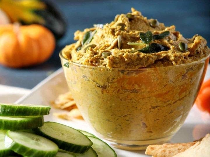 Close up of Sage Pumpkin Hummus, served with cucumber slices, carrots and pita chips