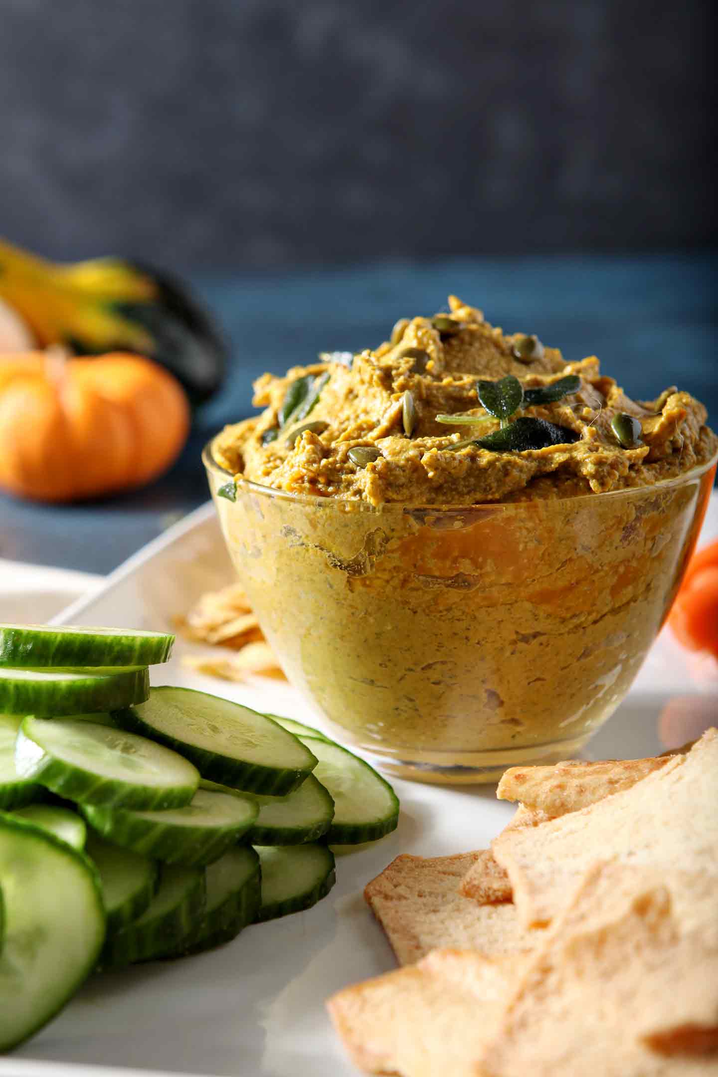 Close up of Sage Pumpkin Hummus, served with cucumber slices, carrots and pita chips