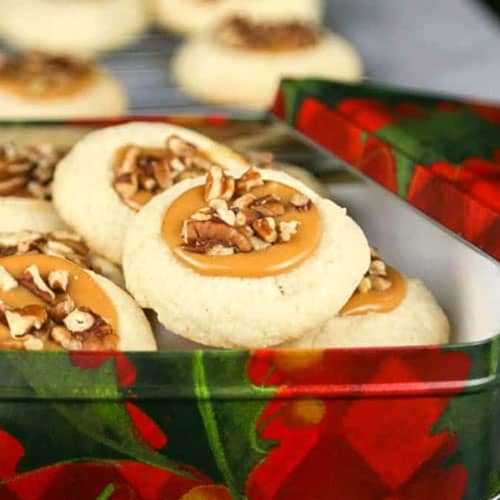 A christmas tin filled with caramel pecan thumbprint cookies.