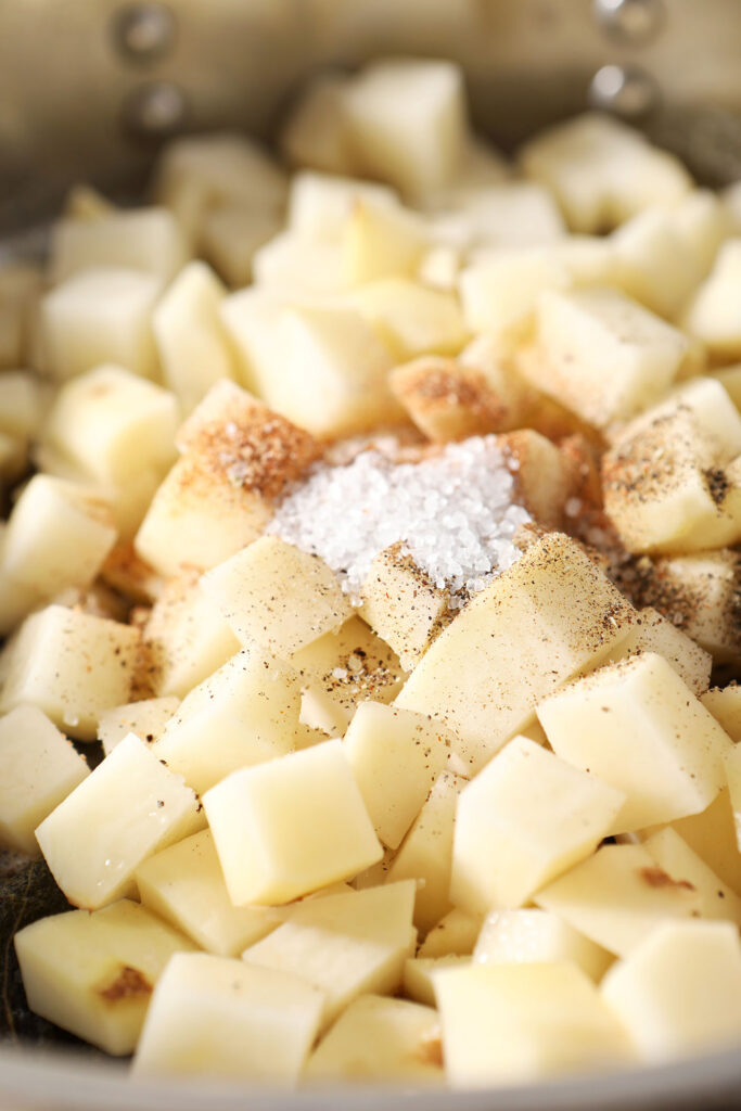 Seasonings sit on top of diced potatoes in a skillet