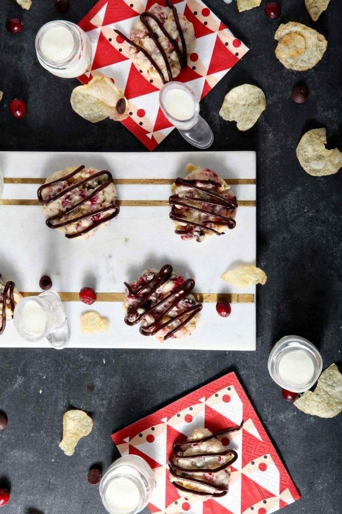 cranberry chocolate potato chip cookies on a white serving tray with milk in glasses