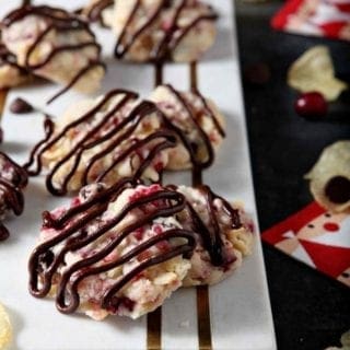 close up of cranberry chocolate potato chip cookies with a chocolate drizzle