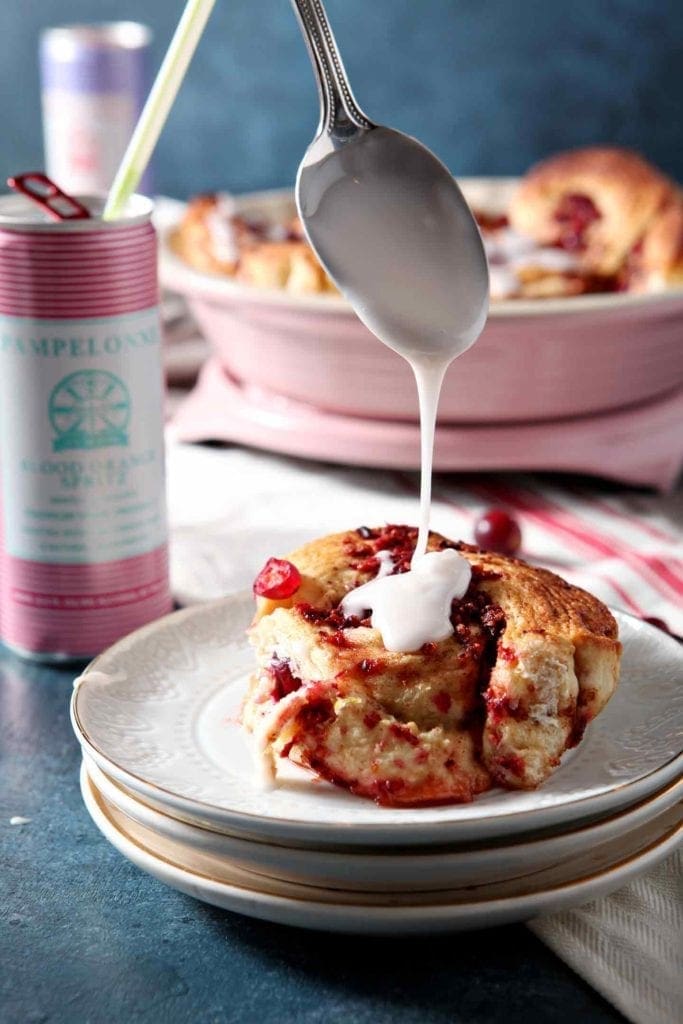 Icing is drizzled on top of a Cranberry Cinnamon Roll.