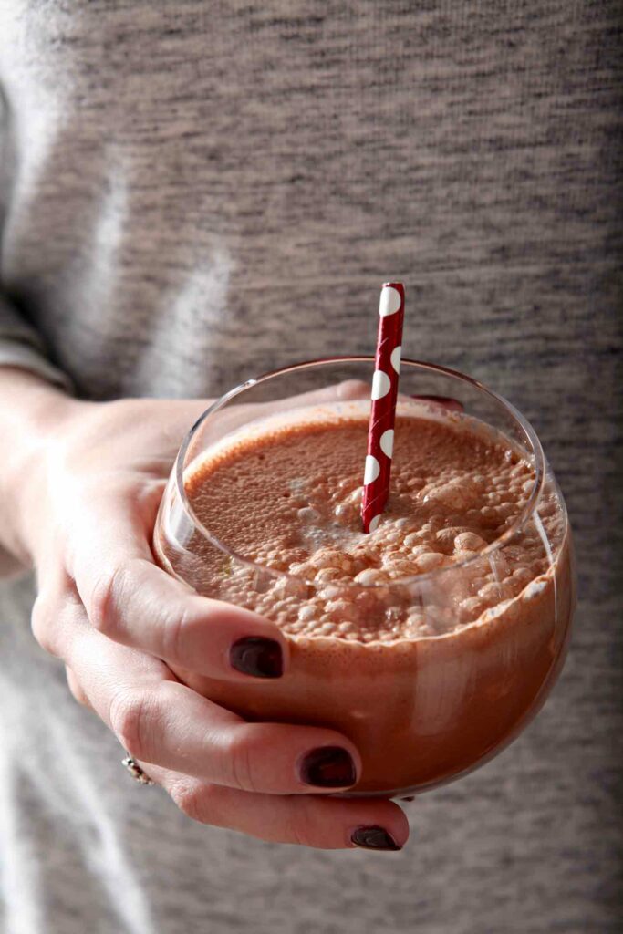 A woman holds a glass of a fall flavored cold brew drink