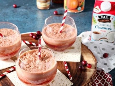 Three Cranberry Pumpkin Cold Brew Coffee Drinks in glasses on a napkins atop a wooden serving platter