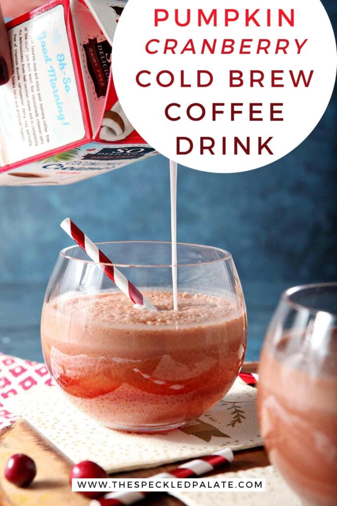 Pumpkin creamer is poured into a cold brew coffee drink in a glass on a wooden serving tray with the text 'pumpkin cranberry cold brew coffee drink'