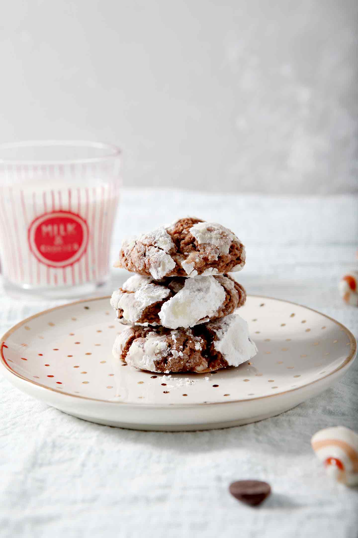 Peppermint Chocolate Crinkle Cookies are stacked on top of each other and served with milk