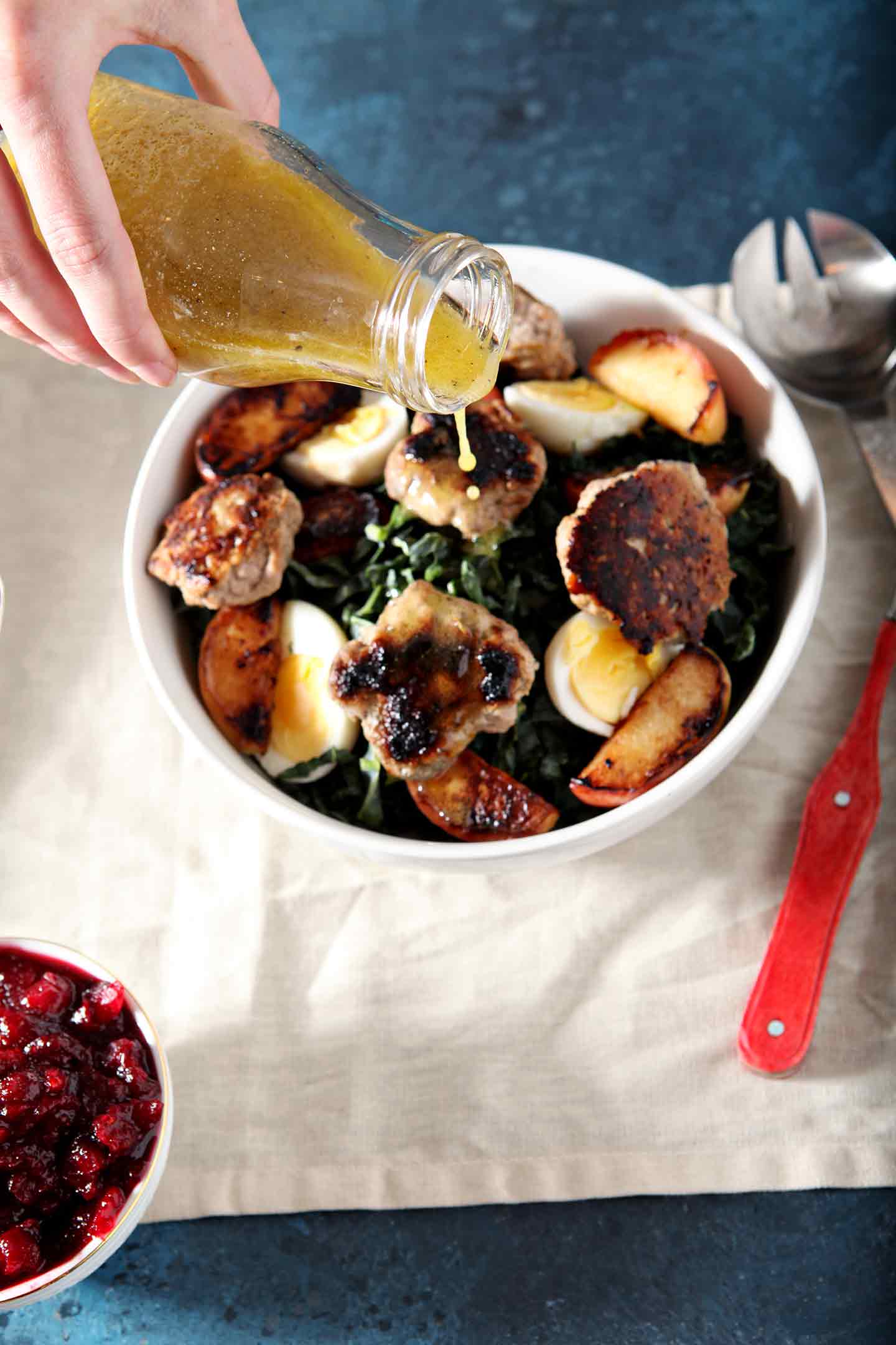 pouring dressing on a thanksgiving brunch salad