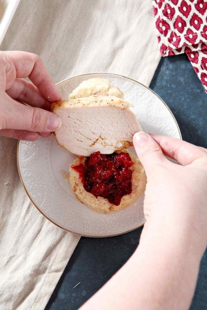 hands holding turkey over a plate