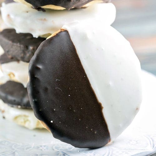 A close up on a black and white cookie with a stack of cookies behind it.