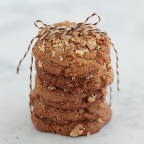 A vertical stack of brown sugar spice pecan cookies tied with a christmas string with a bow on top.