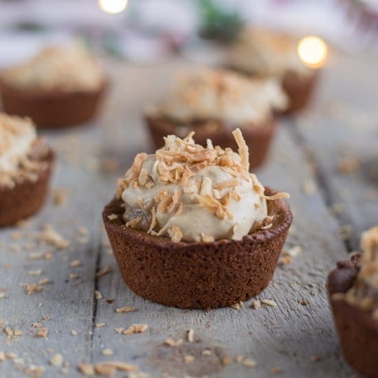 A close up of Gingerbread Cookie Cups topped with spiced pear frosting and toasted coconut.