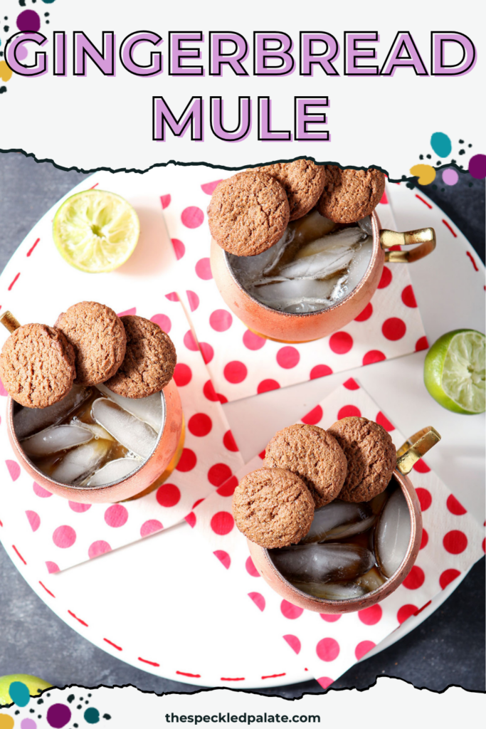 Three copper mugs holding Gingerbread Mules, garnished with ginger snaps, sit on a white platter with decorative dotted red napkins on a dark surface with the text gingerbread mule