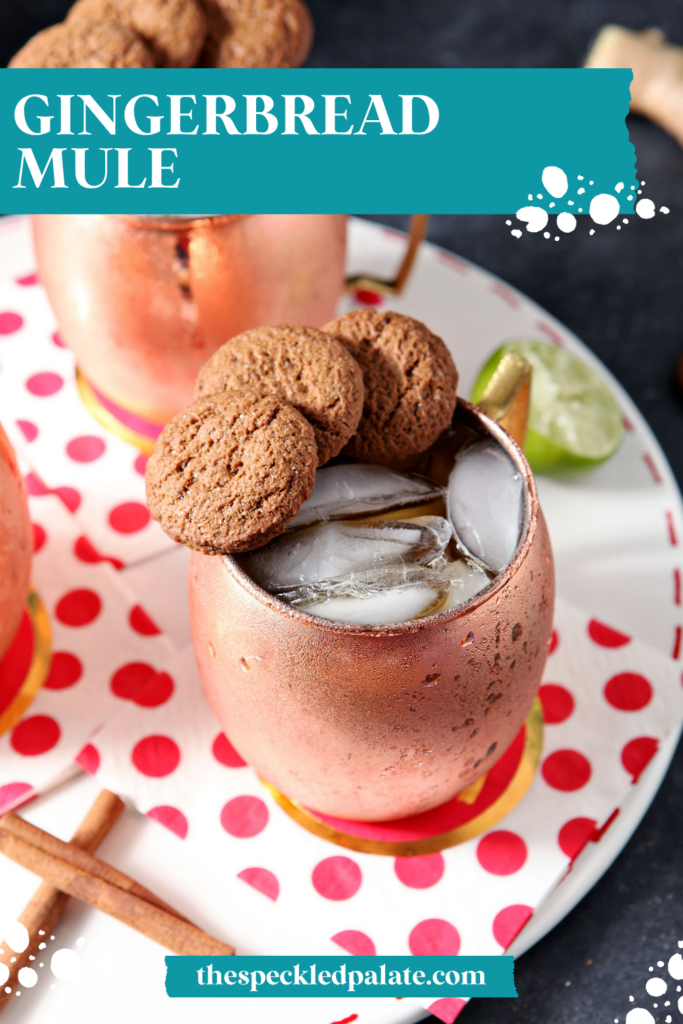 Two copper mugs of drinks, garnished with three gingersnaps on the rim, sit on a white tray with decorative red and white napkins with the text gingerbread mule