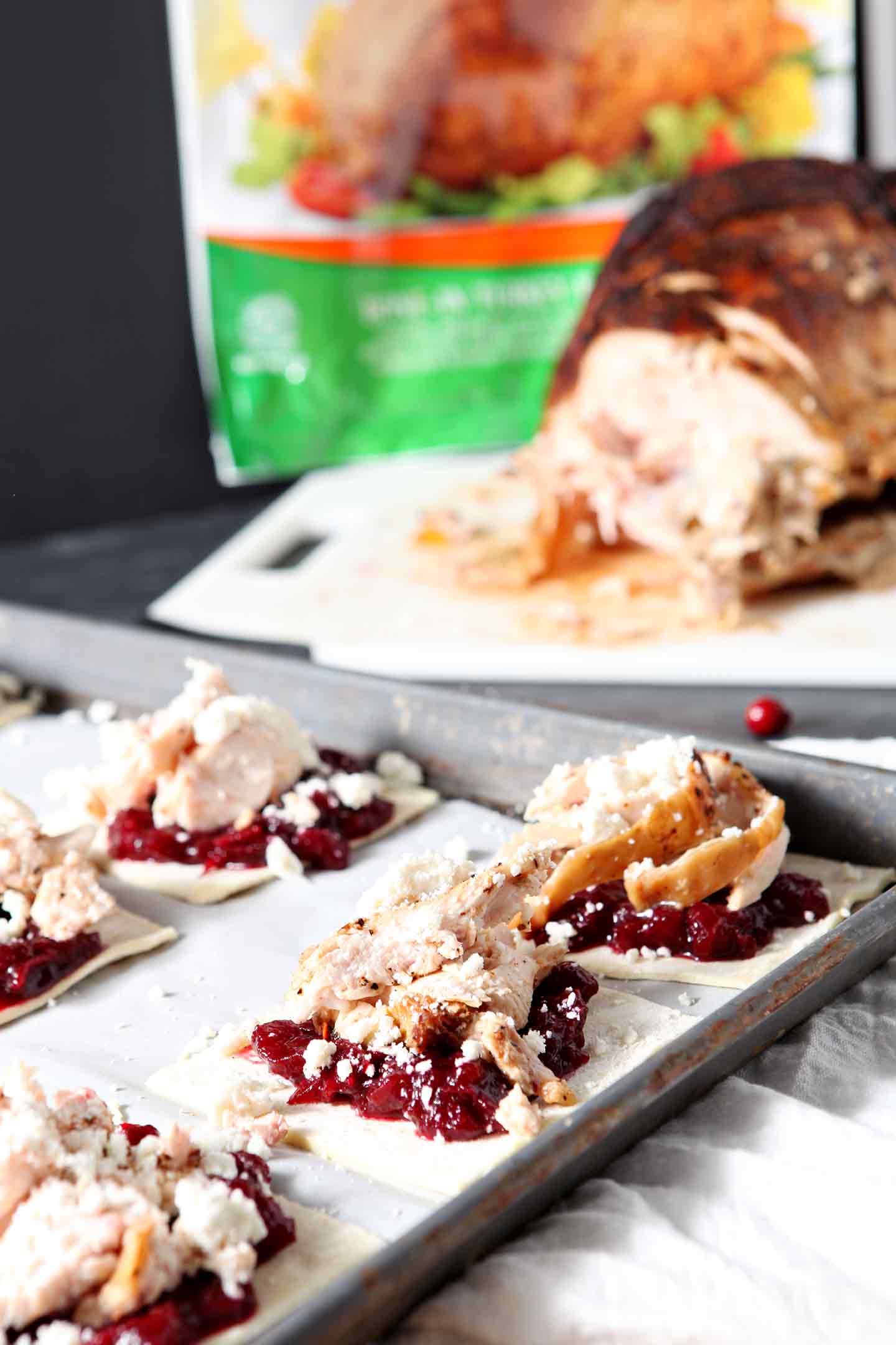 cranberry turkey tartlets on a white plate with turkey in the background