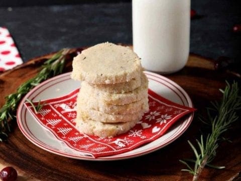a stack of ginger rosemary shortbread cookies on a plate with milk