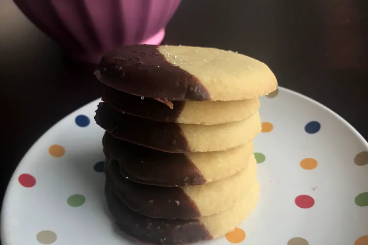 A stack of mint dipped shortbread cookies on a multicolored polka dot plate.