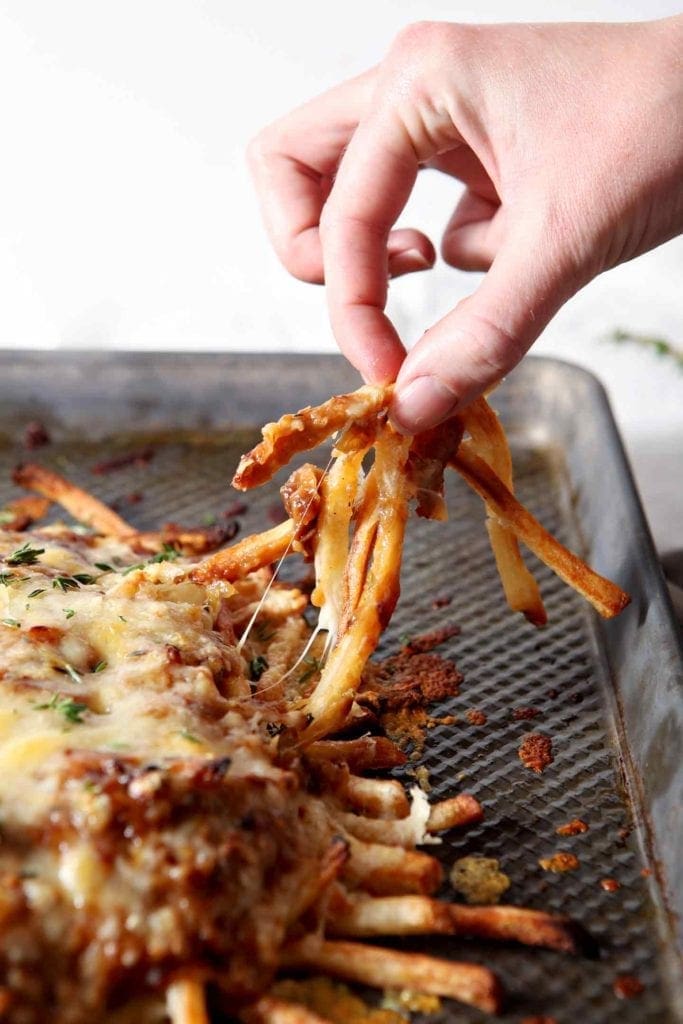 Fries from French Onion Poutine being pulled away from the baking sheet before eating