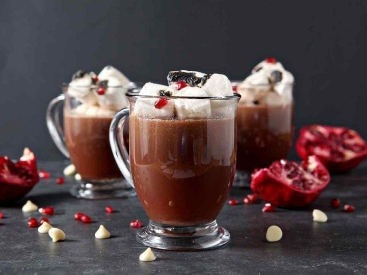 3 pomegranate white hot chocolates in glasses with marshmallows