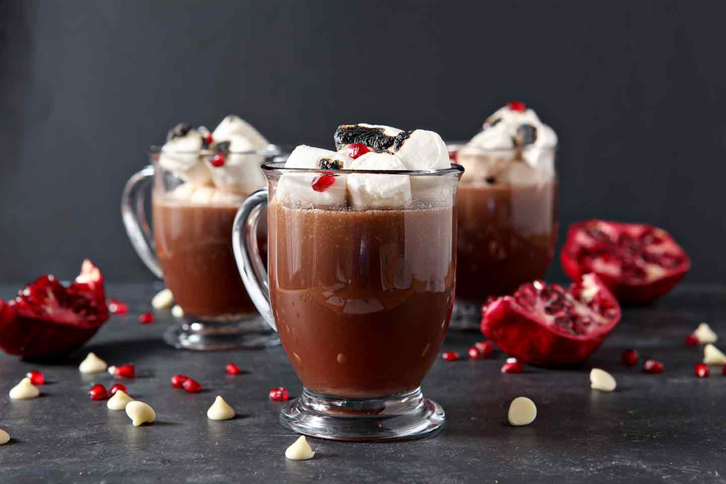 3 pomegranate white hot chocolates in glasses with marshmallows