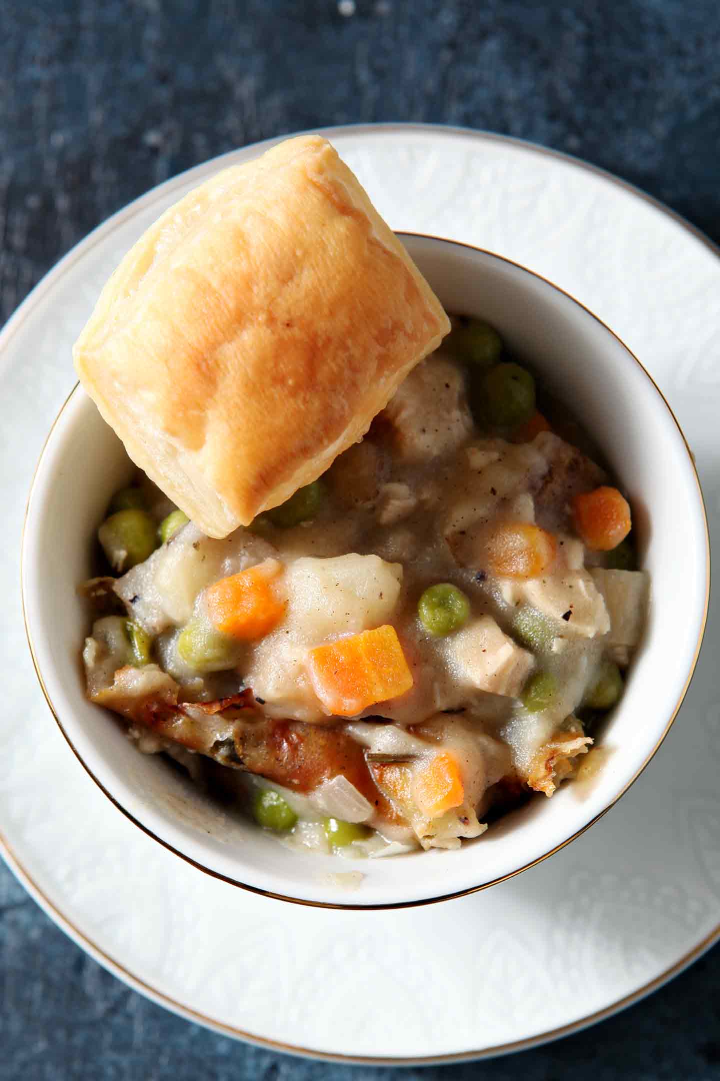 chicken pot pie in a white bowl with a biscuit