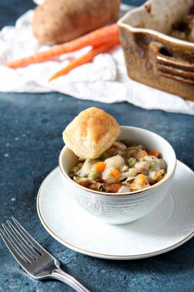 chicken pot pie in a white bowl with a biscuit