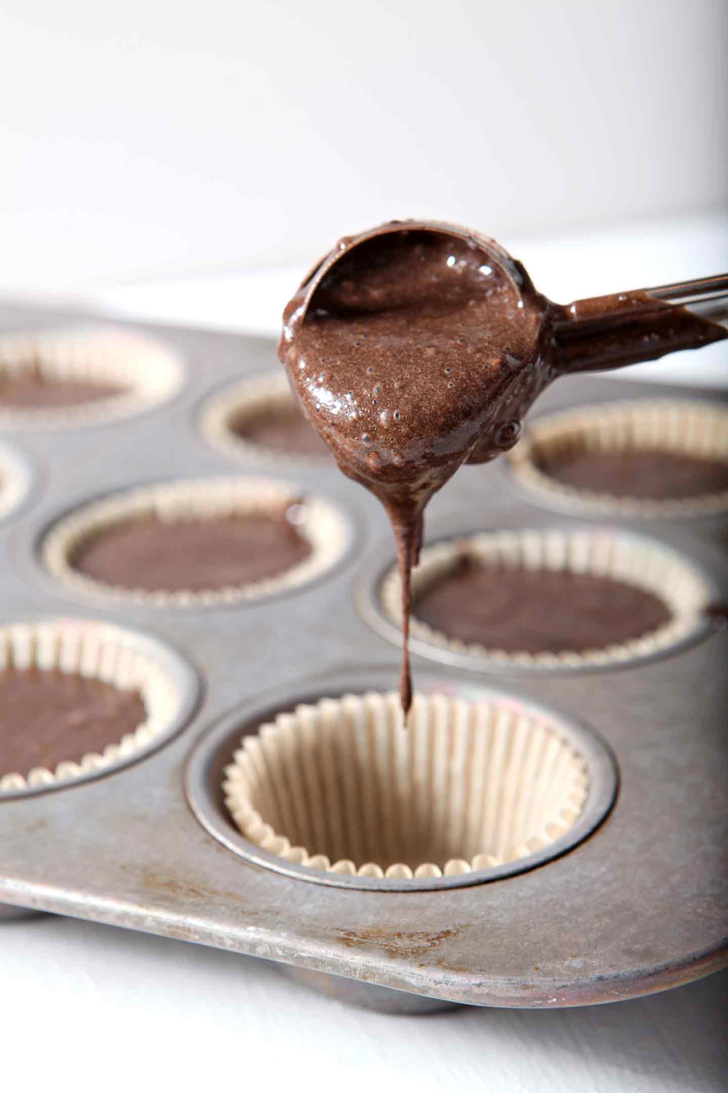 Cupcake batter being poured into cupcake liners before baking