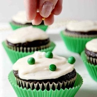 Chocolate Guinness Cupcakes, iced with Bailey's Icing, being decorated with green, white and gold sprinkles