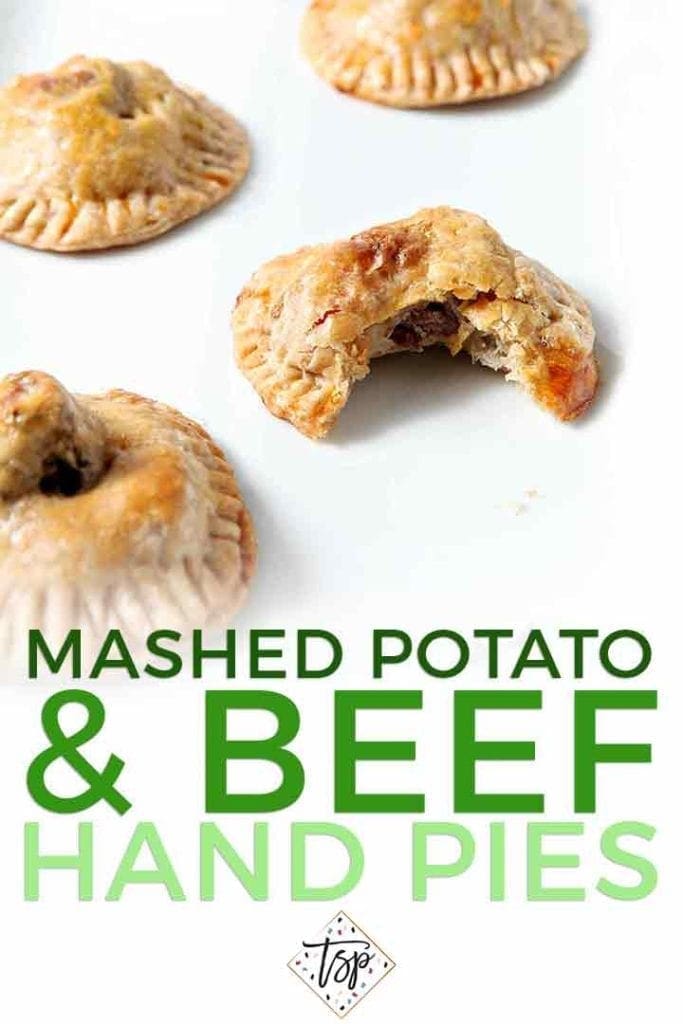 Closeup of a bitten-into Mashed Potato Beef Hand Pies with others on a white platter with the text 'Mashed Potato & Beef Hand Pies'