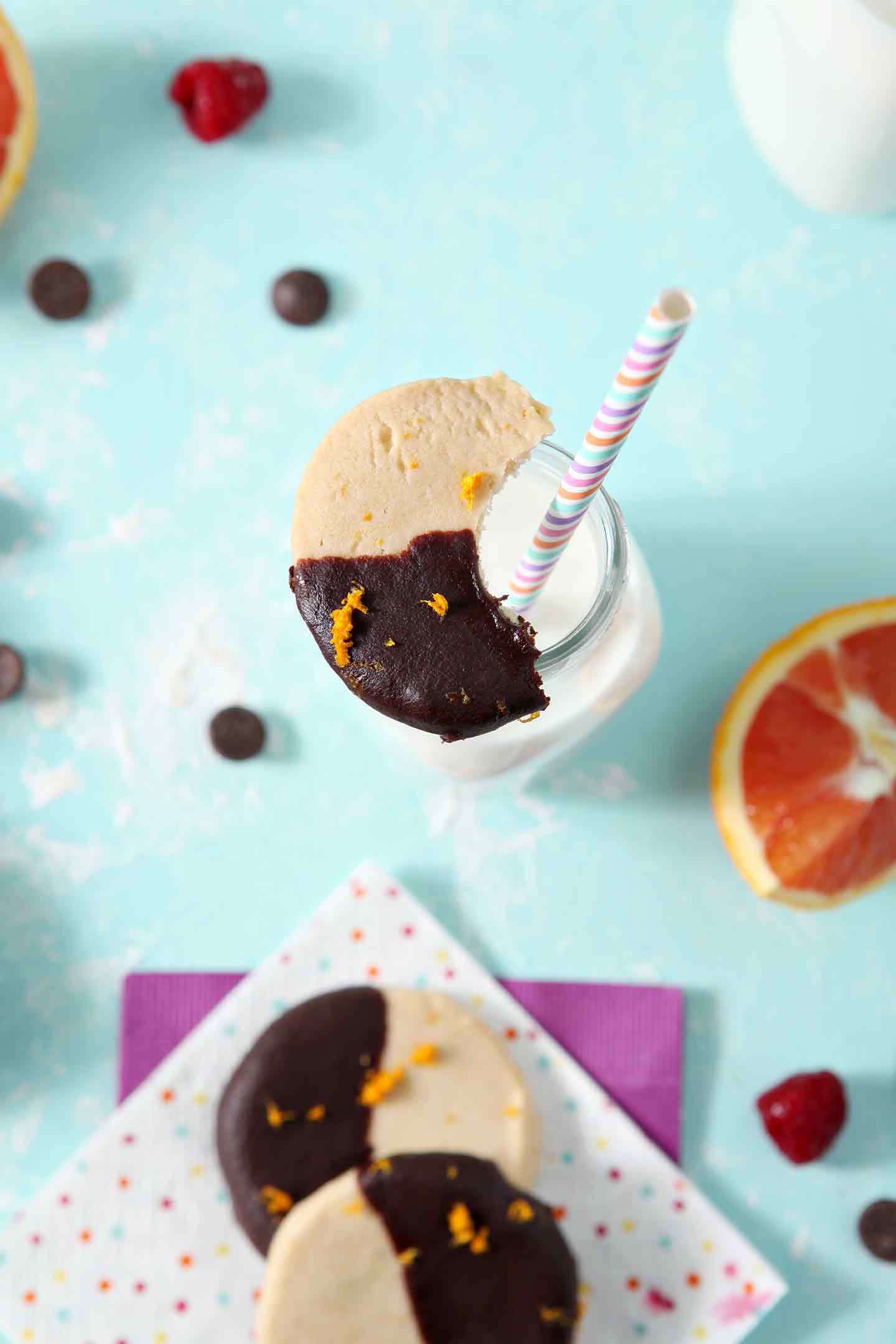 A half-eaten Orange Raspberry Shortbread Cookie sits on top of a bottle of milk