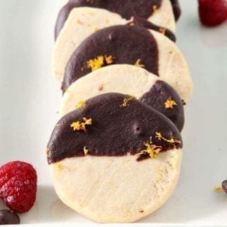 Horizontal image of Orange Raspberry Shortbread Cookies stacked on a white serving platter