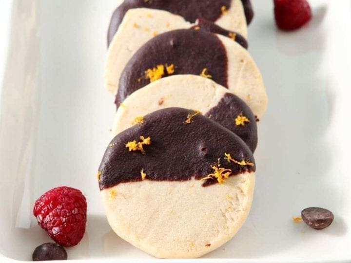 Horizontal image of Orange Raspberry Shortbread Cookies stacked on a white serving platter