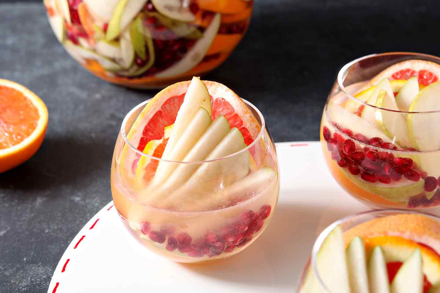 A glass is garnished with pear slices, grapefruit and orange slices with pomegranate arils