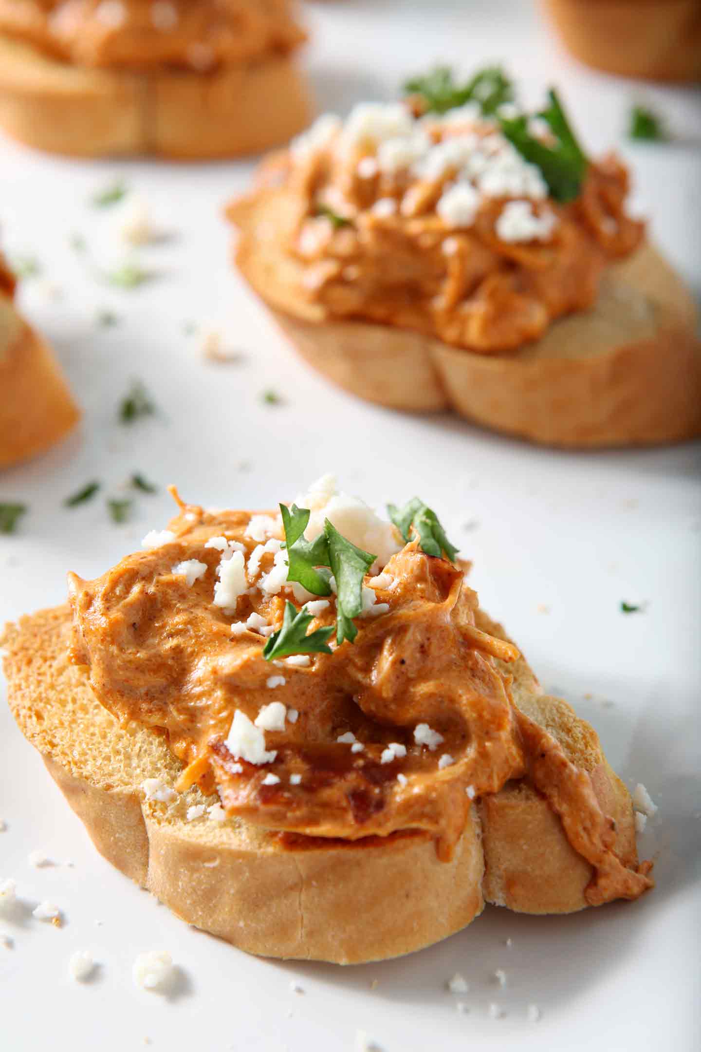 Close up of Chicken Enchilada Bruschetta lined up on a white platter before serving